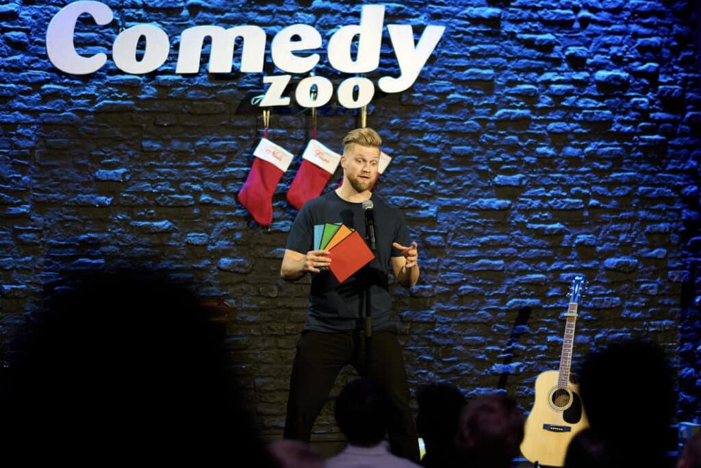 Anders Andresen with coloured cards on stage at the Christmas show at Comedy Zoo in Copenhagen