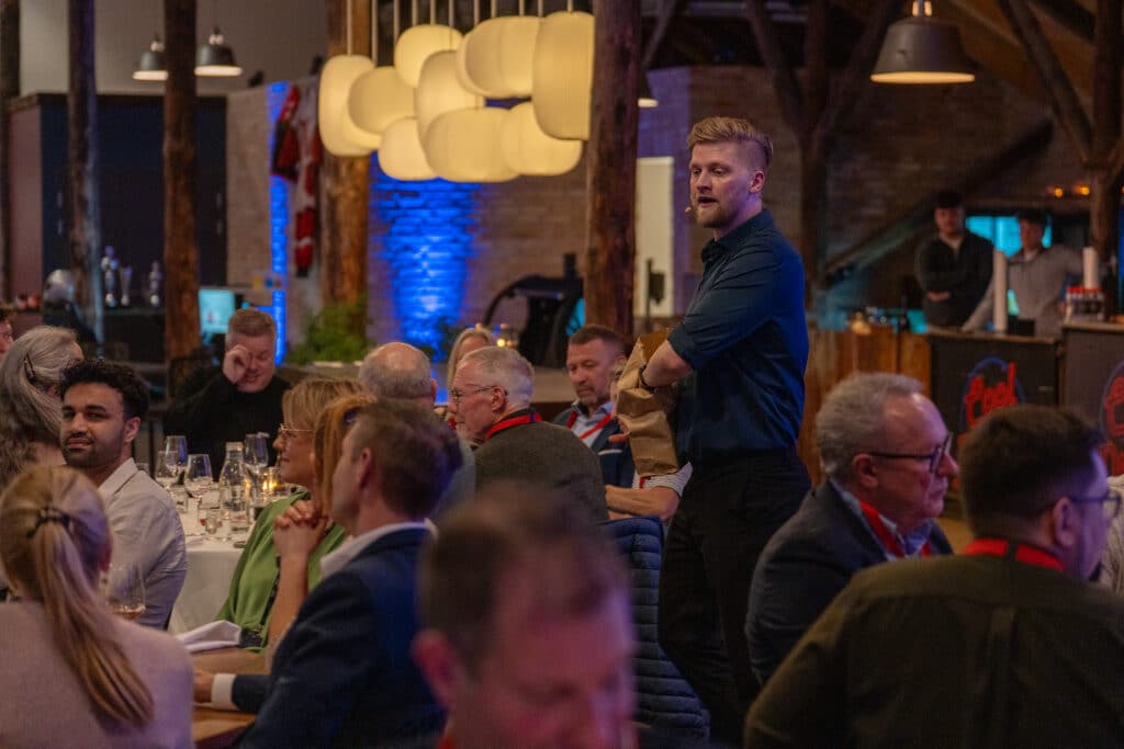 Anders Andresen underholder gæsterne til en firmafest, hvor de sidder ved festlige borde