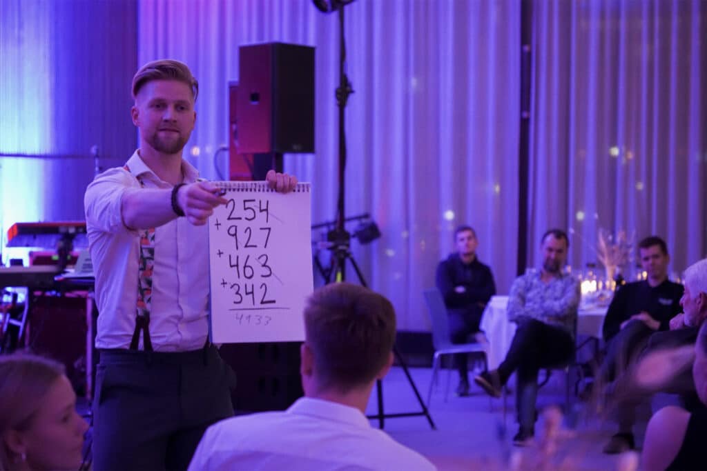 Anders Andresen shows a board of numbers for a magic trick to guests at a company party in Copenhagen